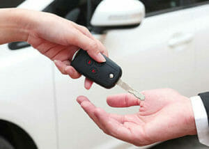 A California lemon law attorney may be needed for the buyer of a new car who is being handed a key.