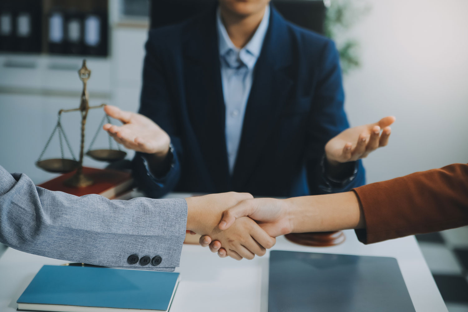 Parties shaking hands while attorneys review settlement paperwork, illustrating how mediation can resolve a California personal injury claim without going to trial.