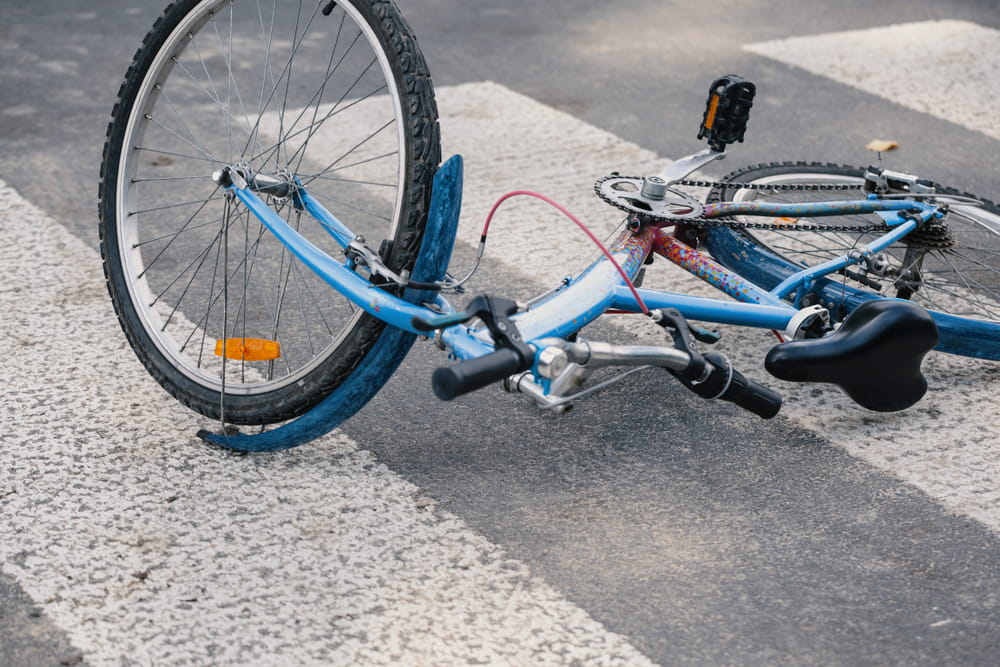 A bicycle lying on its side in a crosswalk after a collision, illustrating the dangers cyclists face at Irvine intersections where drivers fail to yield.
